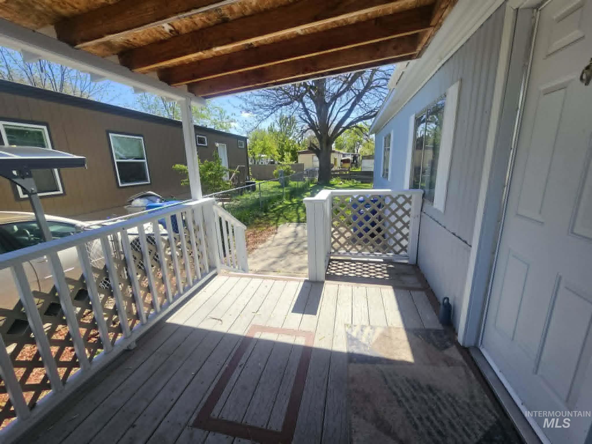 461 Greenleaf Street Boise, ID 83713 - Photo 13 of 19 Covered porch with exposed wood ceiling beams, white railing, decorative lattice panel, and a light-colored entry door