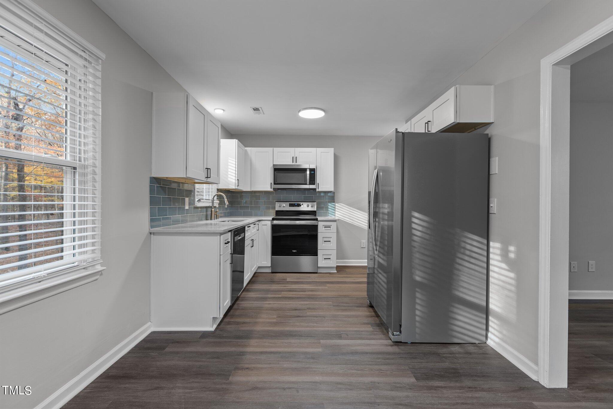 6415 Whitt Road Durham, NC 27712 - Photo 11 of 37 a kitchen with granite countertop a refrigerator and a stove top oven