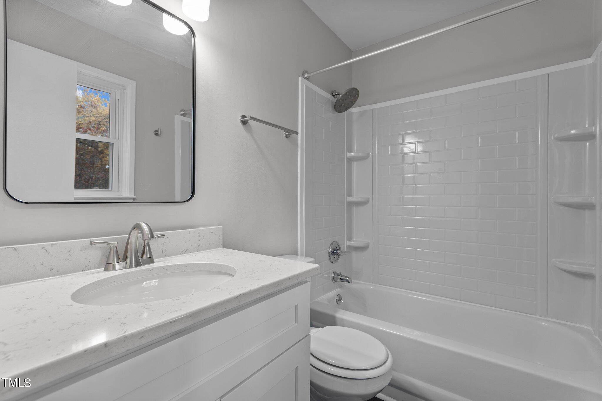 6415 Whitt Road Durham, NC 27712 - Photo 25 of 37 a bathroom with a granite countertop bathtub shower sink vanity mirror and toilet