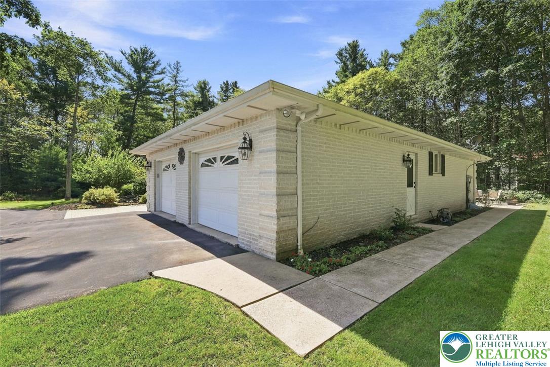 123 Meadow Road Blakeslee, PA 18610 - Photo 45 of 53 A detached multi-car garage with brick siding sits nestled alongside mature trees.