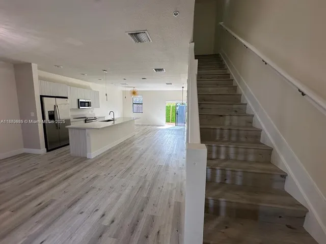 a view of a kitchen with wooden floor and electronic appliances