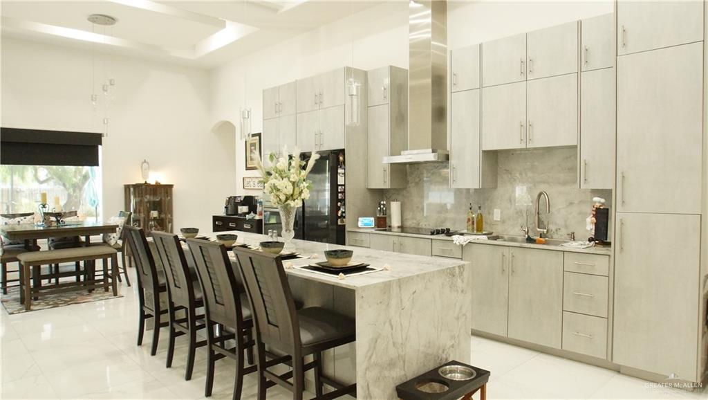 414 Ric Mar Street Edinburg, TX 78541 - Photo 14 of 36 Open-concept kitchen featuring an expansive island with seating, integrated stainless steel appliances, a complementary backsplash, extensive upper and lower cabinetry, and recessed lighting