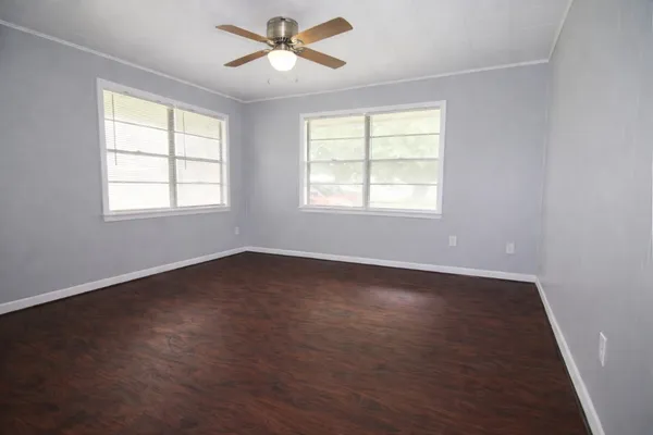 a view of an empty room with wooden floor and a window