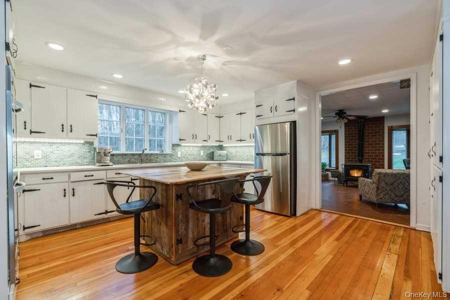 1141 Beekman Road Hopewell Junction, NY 12533 - Photo 7 of 36 a kitchen with stainless steel appliances granite countertop a kitchen island a stove a refrigerator a sink a dining table and chairs with wooden floor