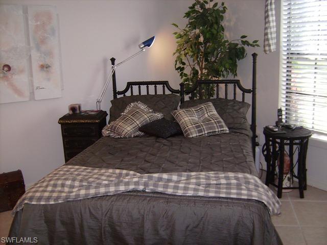 265 Deerwood Circle, Unit 3 Naples, FL 34113 - Photo 6 of 14 a bedroom with a bed window and table chair