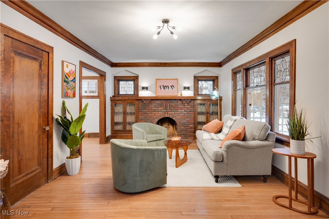 2016 Rossmoor Road Cleveland Heights, OH 44118 - Photo 7 of 46 Living area with crown molding, a brick fireplace, light wood finished floors, and healthy amount of natural light