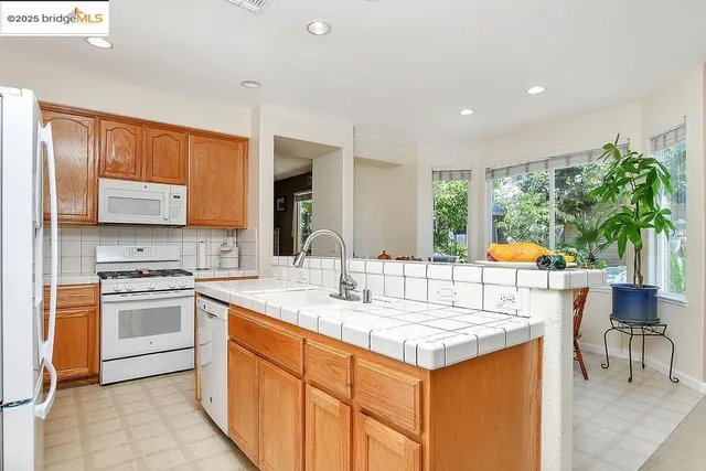 a kitchen with stainless steel appliances granite countertop a refrigerator a sink and a stove