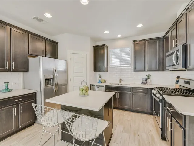 a kitchen with a sink a stove a refrigerator cabinets and wooden floor