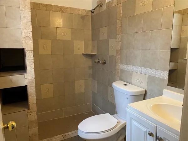 a white toilet sitting next to a bathroom sink and a shower