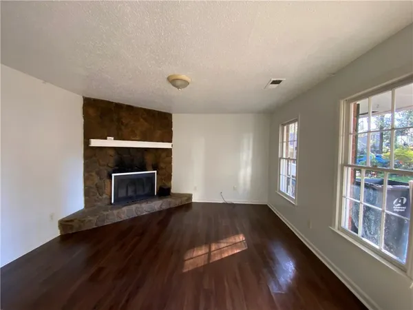 an empty room with wooden floor fireplace and windows