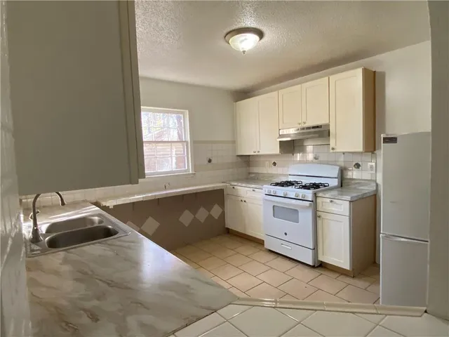 a kitchen with a stove sink and cabinets
