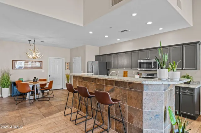 a kitchen with stainless steel appliances kitchen island granite countertop a table chairs sink and cabinets