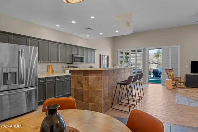 a kitchen with stainless steel appliances granite countertop a refrigerator a stove top oven a dining table and chairs