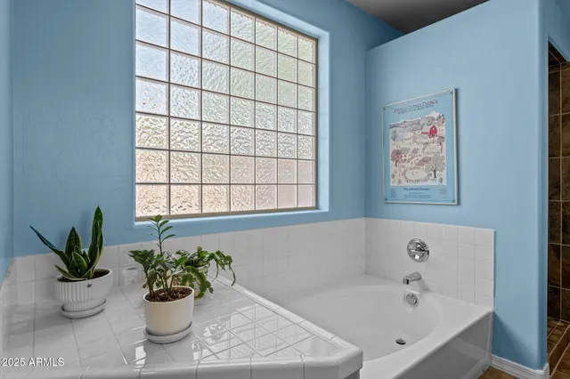 a white bath tub sitting in a bathroom next to a window