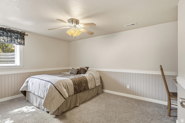 2420 West Old Hwy Road Morgan, UT 84050 - Photo 35 of 54 Bedroom featuring wainscoting, ceiling fan, carpet flooring, and a textured ceiling