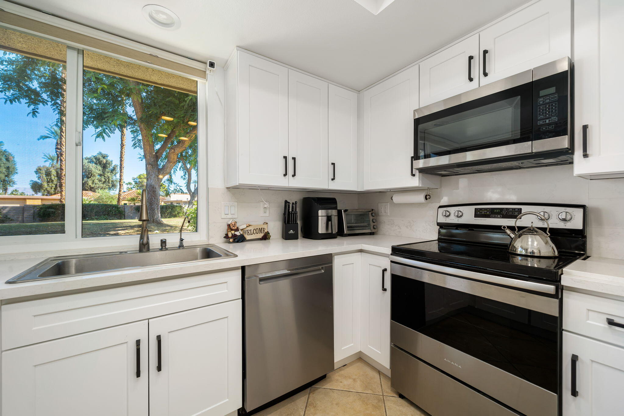 38 Malaga Drive Rancho Mirage, CA 92270 - Photo 3 of 22 a kitchen with stainless steel appliances granite countertop a sink a stove a microwave and wooden cabinets
