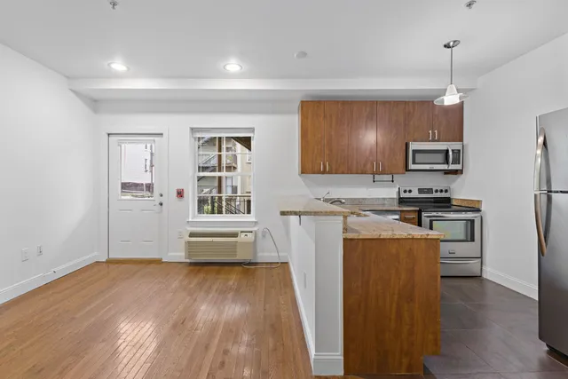 a kitchen with granite countertop a refrigerator stove top oven and sink