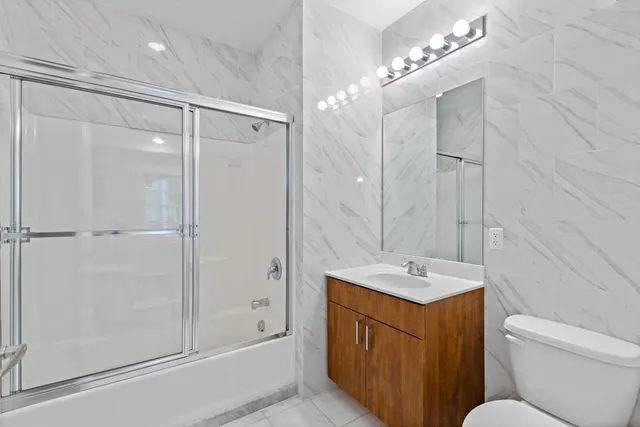 a bathroom with a granite countertop sink a toilet and shower