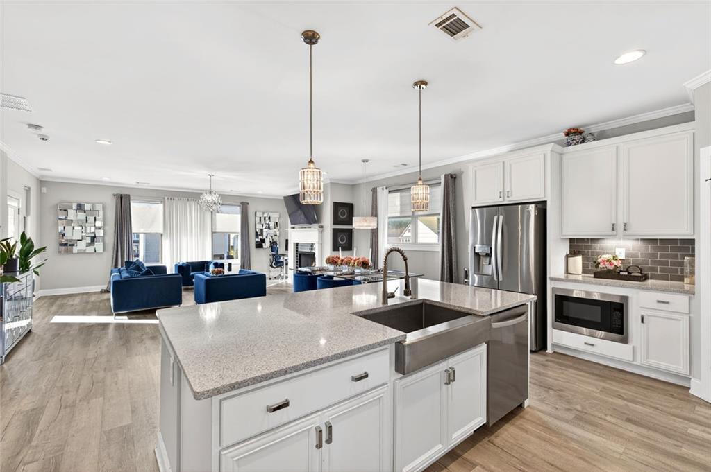 5259 Cloud Street Stone Mountain, GA 30083 - Photo 11 of 38 a kitchen with stainless steel appliances a center island a refrigerator a stove a sink dishwasher and white cabinets with wooden floor