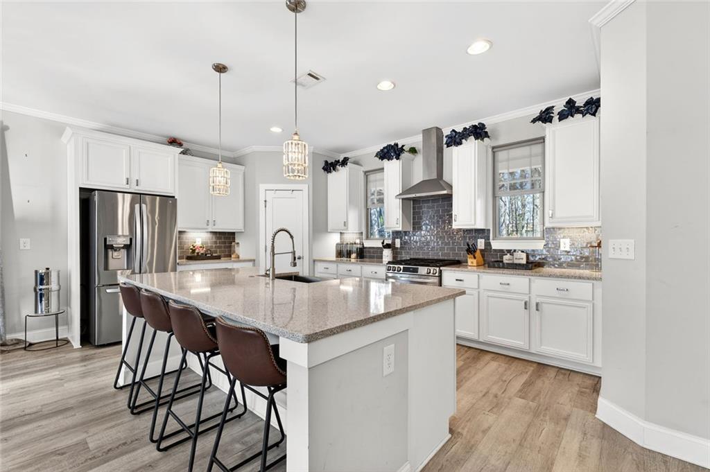 5259 Cloud Street Stone Mountain, GA 30083 - Photo 7 of 38 a kitchen with stainless steel appliances kitchen island granite countertop a table chairs stove and white cabinets