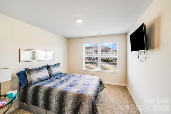 a bedroom with a bed a flat screen tv and windows