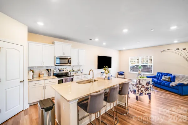 a kitchen that has a lot of cabinets a sink a stove and wooden floor