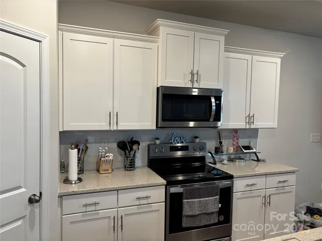 a kitchen with stainless steel appliances granite countertop white cabinets and a stove a oven with white countertops