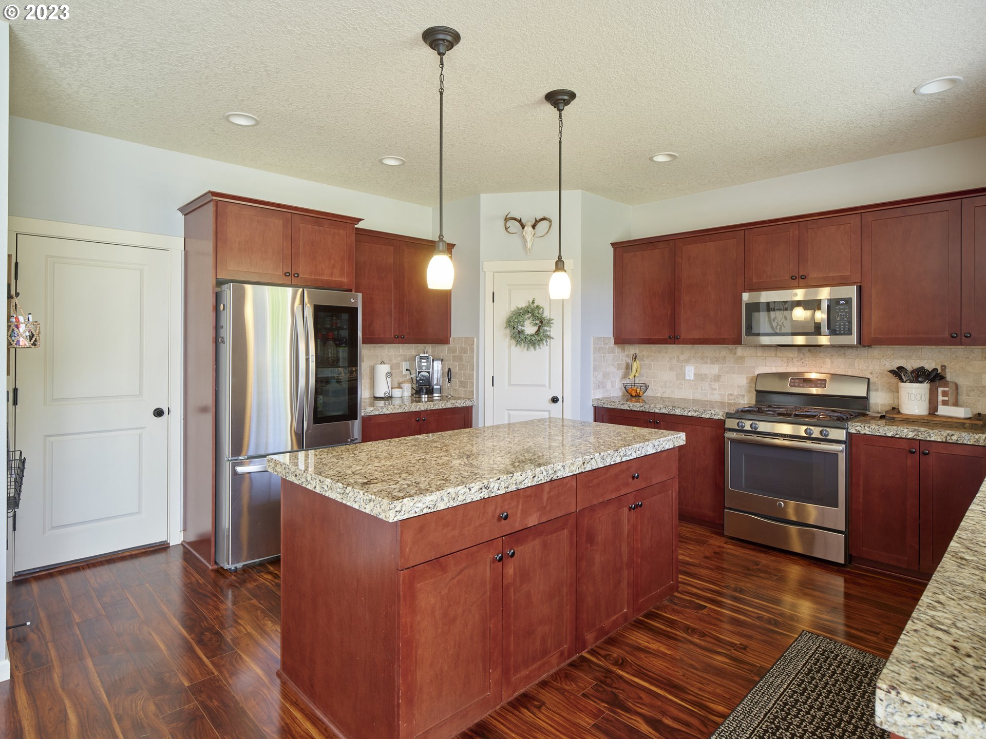 3551 North 1st Street Ridgefield, WA 98642 - Photo 12 of 38 a kitchen with stainless steel appliances granite countertop wooden cabinets a refrigerator a sink a stove and a wooden floors
