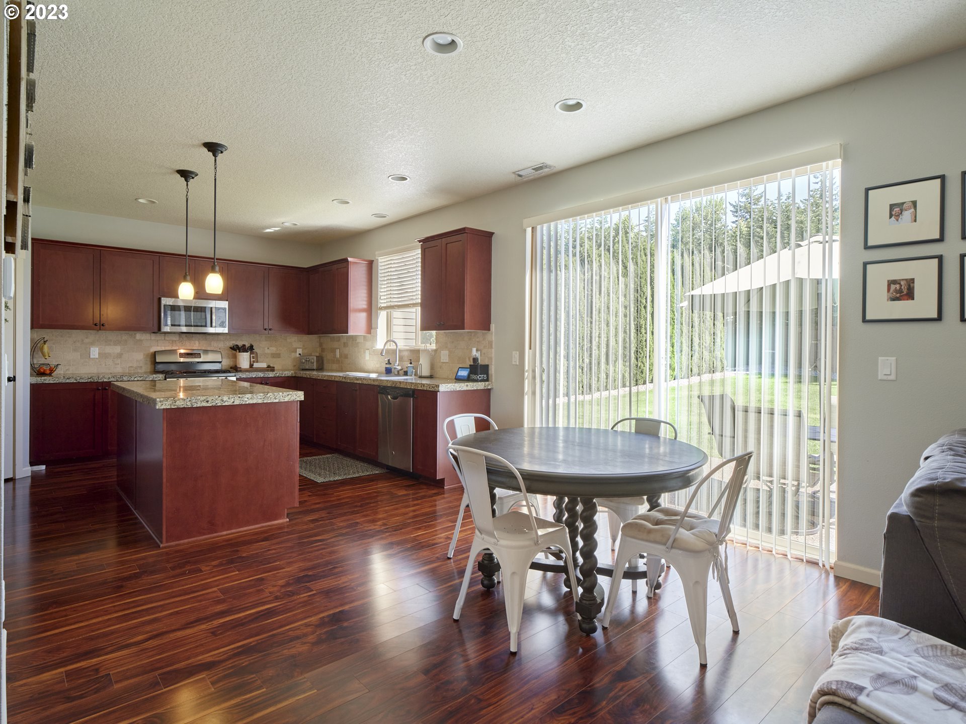3551 North 1st Street Ridgefield, WA 98642 - Photo 13 of 38 a kitchen with stainless steel appliances granite countertop a stove a refrigerator a kitchen island a dining table and chairs with wooden floor
