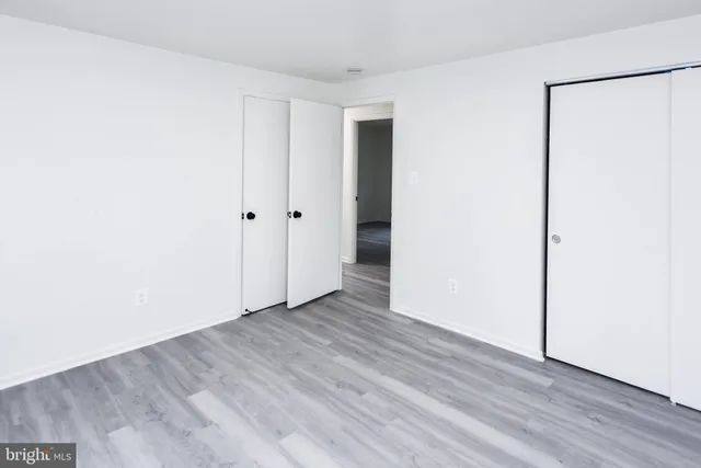 a view of an empty room with wooden floor and a fireplace