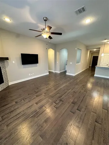 a view of an empty room with wooden floor and a ceiling fan