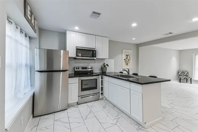 a kitchen with stainless steel appliances granite countertop a refrigerator stove a sink and a microwave