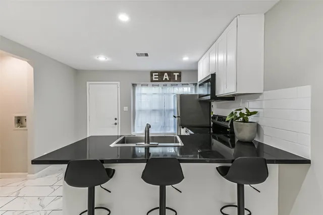 a kitchen with stainless steel appliances granite countertop a sink and a refrigerator