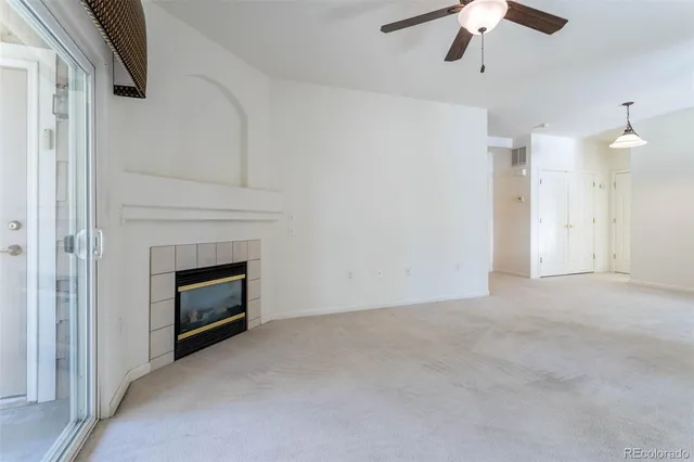 an empty room with chandelier fan and fireplace