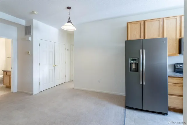 a view of an empty room with window and refrigerator