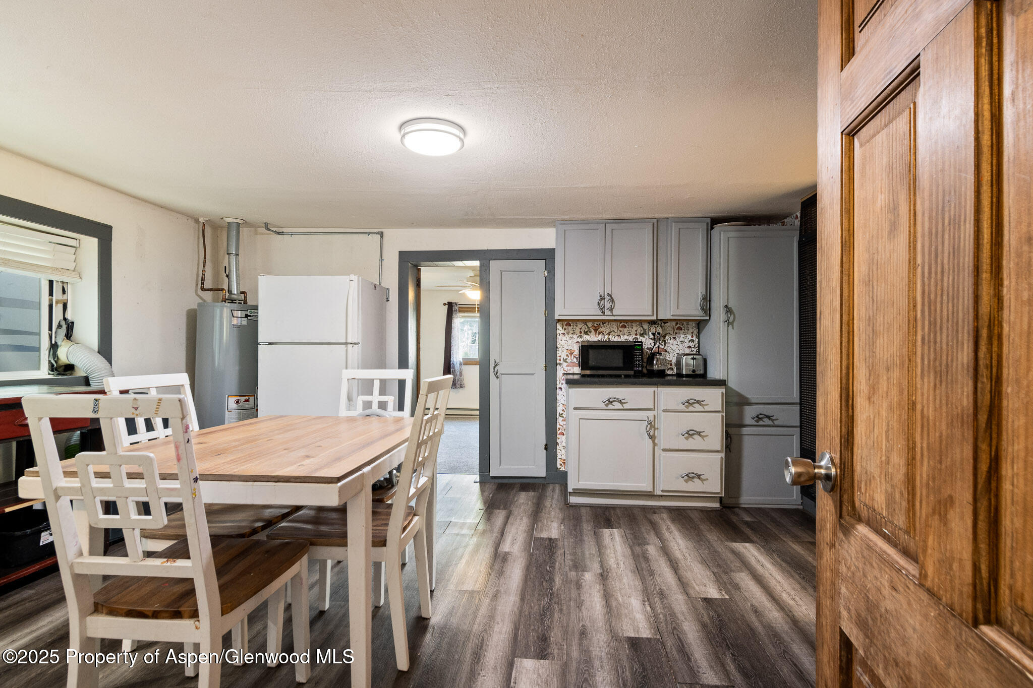 a kitchen with a refrigerator a stove microwave oven with a dining table and chairs with wooden floor