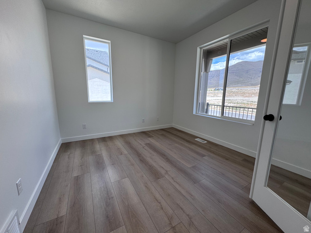 Room featuring wood-finish flooring, white baseboards, and bright white walls