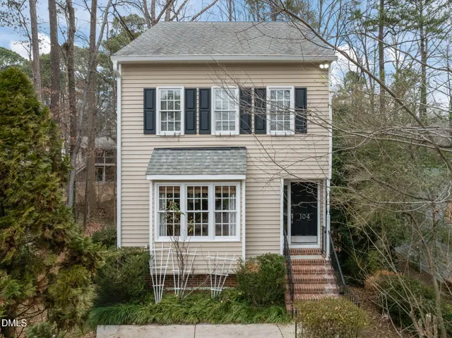 a front view of a house with a yard and trees