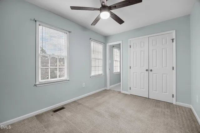 an empty room with window and ceiling fan