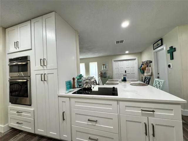 a kitchen with stainless steel appliances kitchen island granite countertop a refrigerator and a stove top oven
