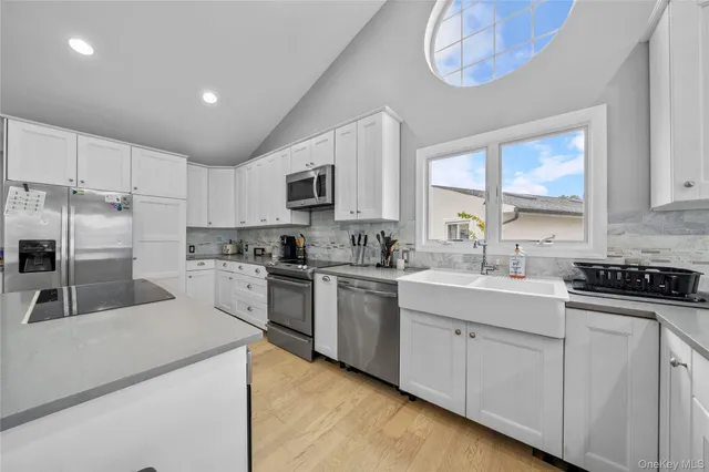 a kitchen with granite countertop a sink a counter top space stainless steel appliances and cabinets