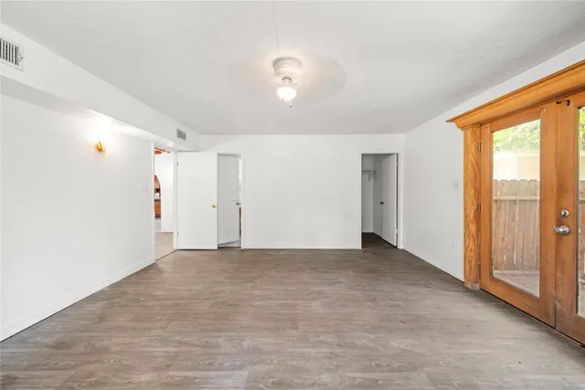 an empty room with wooden floor ceiling fan and windows