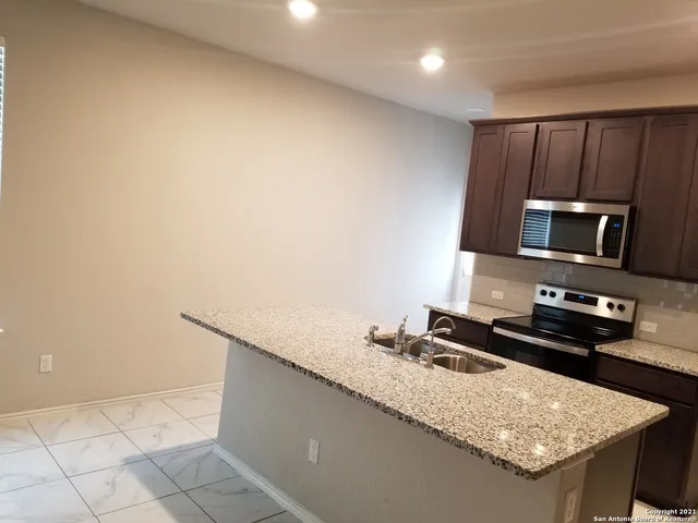 a kitchen with granite countertop a sink a stove top oven a granite counter top and cabinets