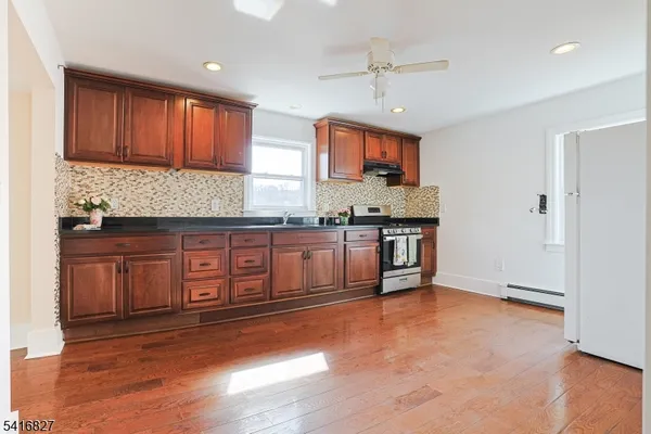 a kitchen with stainless steel appliances granite countertop a stove a sink dishwasher and a refrigerator with wooden floor