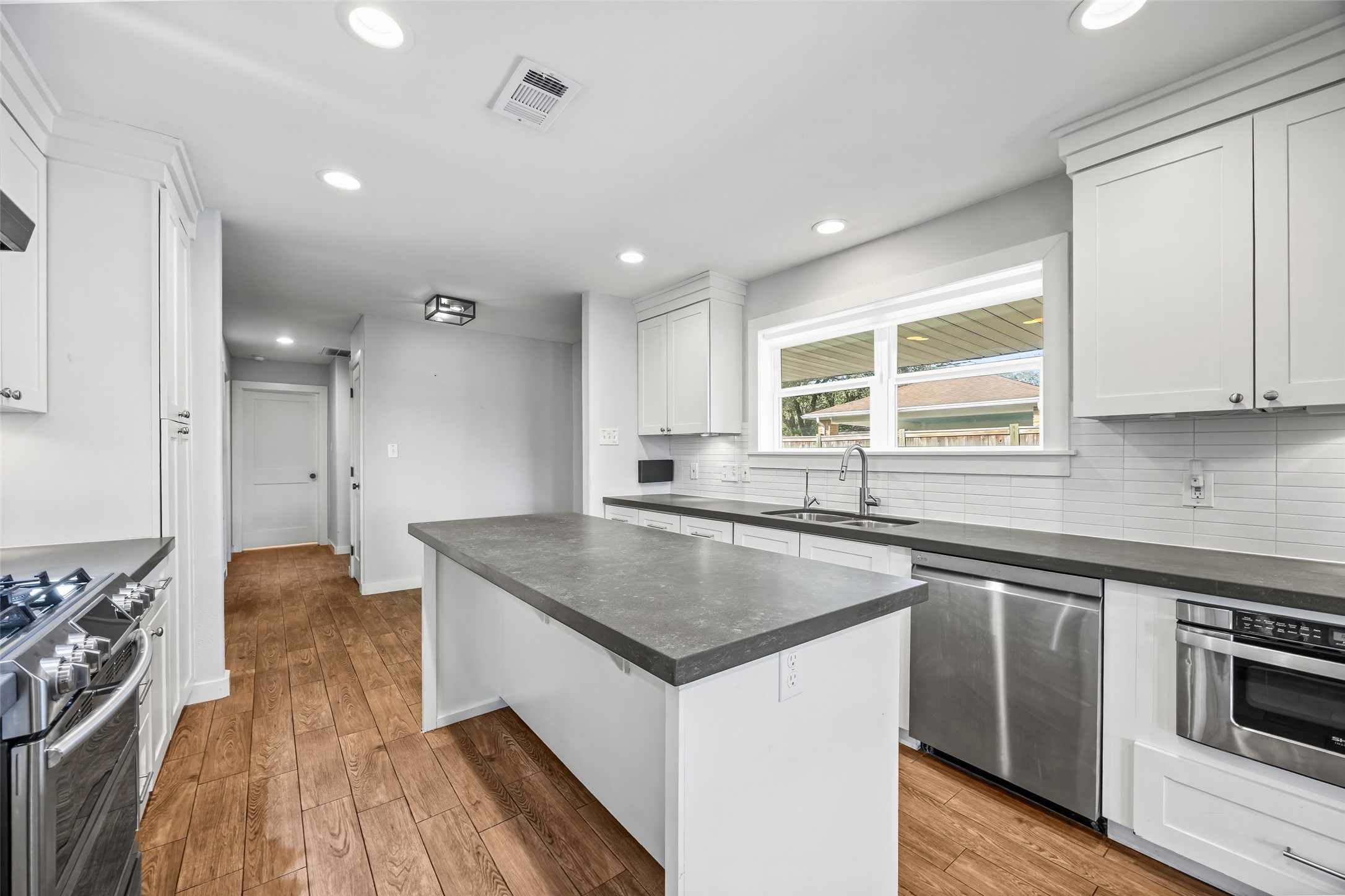 9715 Greenwillow Street Houston, TX 77096 - Photo 9 of 31 a kitchen with stainless steel appliances granite countertop a sink stove and wooden floor