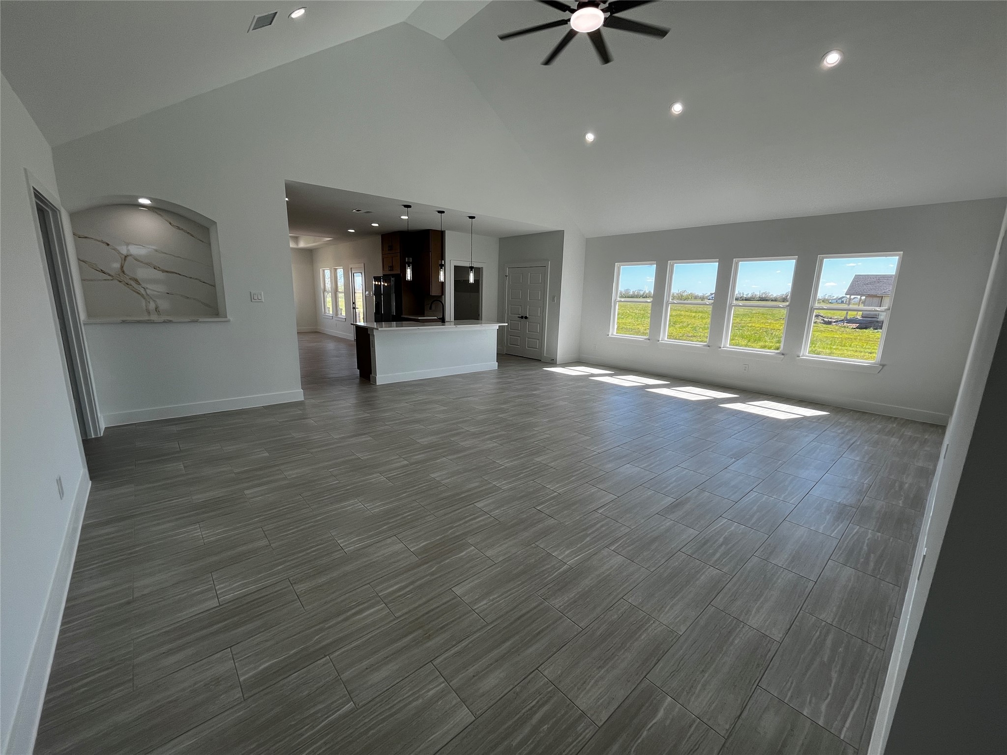 471 Buffalo Trail Angleton, TX 77515 - Photo 8 of 35 This spacious living area features high ceilings, large windows with ample natural light, modern tile flooring, and an open layout leading to a kitchen with a central island. Ideal for bright, airy living.