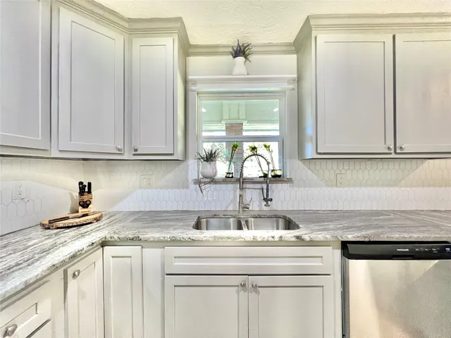 a kitchen with granite countertop a sink cabinets and stainless steel appliances