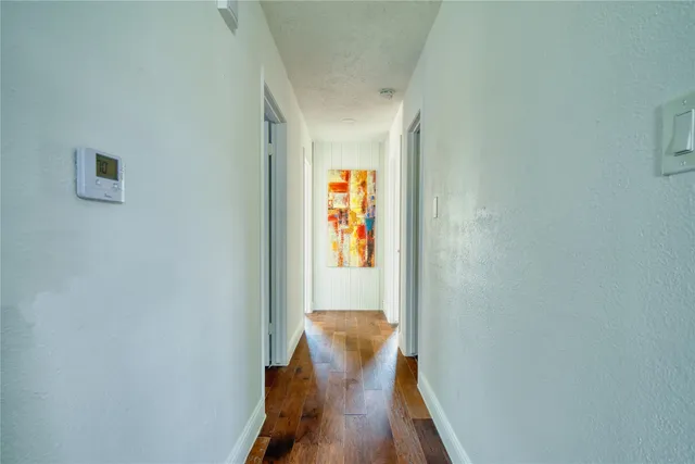 a view of a hallway with wooden floor and a dining room