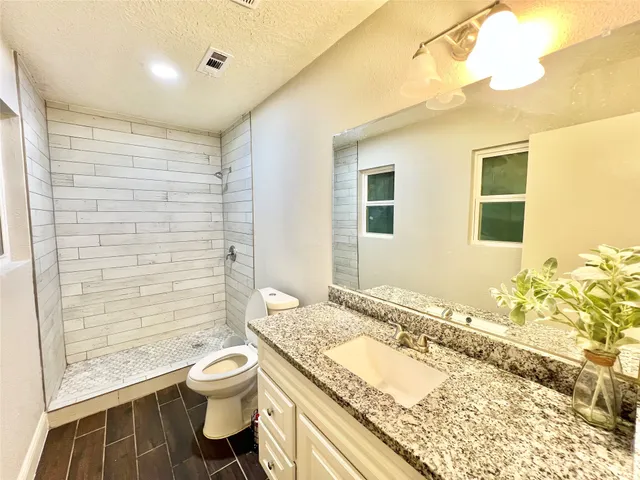 a bathroom with a granite countertop toilet sink and shower