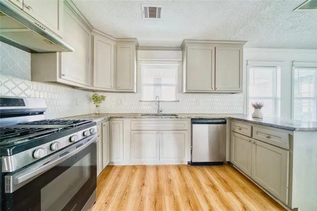 a kitchen with granite countertop a sink stainless steel appliances and cabinets